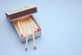 Matches in an open box on a pale blue paper table Royalty Free Stock Photo