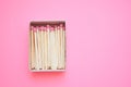 Matches in an open box on a pale pink paper table Royalty Free Stock Photo