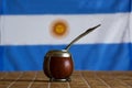 Mate, mate grass yerba mate with flag of Argentina in the bac