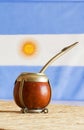 Mate, mate grass yerba mate with flag of Argentina in the bac