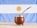 Mate, mate grass yerba mate with flag of Argentina in the bac