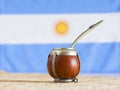 Mate, mate grass yerba mate with flag of Argentina in the background