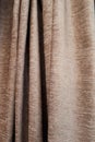 Materials and fabrics. Close-up view of bright brown curtain in thin and thick vertical folds made of dense fabric. Textured