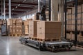materials handling robot, loading box onto pallet, with view of busy warehouse visible in the background