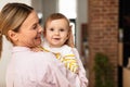 Maternal love. Mother holding cute infant girl on hands and cudding, embracing baby and smiling, bedroom interior Royalty Free Stock Photo