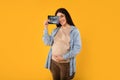 Maternity concept. Happy pregnant woman holding ultrasound photo of her baby and embracing belly on yellow background Royalty Free Stock Photo