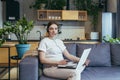 Maternity leave. Work. Pregnant freelancer woman sitting at home on sofa with laptop and in headphones in home clothes. Works on Royalty Free Stock Photo