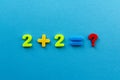 Math action from colored plastic numbers on blue paper background