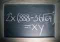 Math algebra equations written on chalkboard with wooden frame in classroom