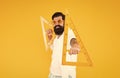 Math genius. Geometry geek holding triangles on yellow background. Geek or nerdy student making angle. Bearded man in