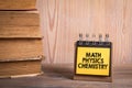 Math Physics Chemistry. Stack of books and a notebook on a shelf