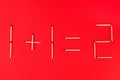 Mathematical addition of numbers using matches on red background