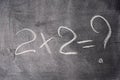 Mathematical example two times two is written in white chalk on a black chalk board Royalty Free Stock Photo