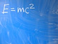 Mathematical formula e=mc2 squared written on a blue, relatively dirty chalkboard by chalk. Located in the upper left corner of