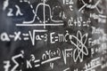 Mathematical operations and quantum physics formulas handwritten on the blackboard