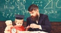 Mathematics lesson concept. Father teaches son mathematics. Teacher in formal wear and pupil in mortarboard in classroom Royalty Free Stock Photo