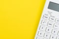 Mathematics, tax calculation, finance or investment concept, white clean calculator on solid yellow background with copy space