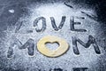 Mather Day Concept. Word LOVE MOM making from the flour and dough on dark background. Top views, close-up Royalty Free Stock Photo