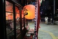 Selective closeup shot of a lighted orange paper lantern near glass windows during nighttime