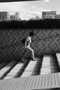 Vertical greyscale shot of a lonely female walking up the stairs