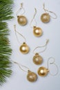 Matt and shiny golden bulbs on strings on light wooden background, plastic decorative Christmas baubles, pine tree branches border Royalty Free Stock Photo