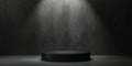 A matte black podium with a smooth surface, placed in front of a textured gray wall, lit by a Royalty Free Stock Photo
