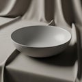 A matte, gray, ceramic bowl sits on a smooth, draped fabric surface Royalty Free Stock Photo