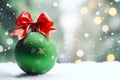 matte green Christmas ball with red bow a snowy background of bokeh lights on a Christmas tree Royalty Free Stock Photo