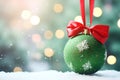 matte green Christmas ball with red bow a snowy background of bokeh lights on a Christmas tree Royalty Free Stock Photo