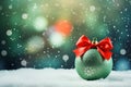 matte green Christmas ball with red bow a snowy background of bokeh lights on a Christmas tree Royalty Free Stock Photo