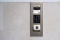 Matte metal intercom call panel with white digital buttons and fingerprint scanner on limestone wall of luxury Royalty Free Stock Photo