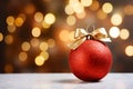 matte red Christmas ball with a gold bow on a snowy background of bokeh lights on a Christmas tree, copy space Royalty Free Stock Photo