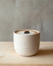A matte white ceramic cup with iced coffee on a light birchwood surface. A single perfect coffee bean on the foam Royalty Free Stock Photo