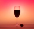 Matte wineglass half red wine orange background cork on table Royalty Free Stock Photo