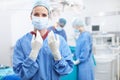 A matter of life and death. Portrait of a female surgeon wearing gloves ready to perform surgery with her colleagues. Royalty Free Stock Photo