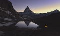 Matterhorn peak reflected in the Riffelsee with a lighted tent