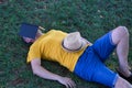 Mature adult Hispanic male lying on the grass, sleeping with a book open on his face and a hat resting on his belly