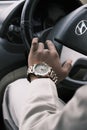 a man driving a car with a gold wrist watch on his wrist