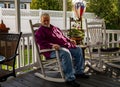 Mature adult male is seated in a wooden rocking chair on an outdoor patio. Royalty Free Stock Photo