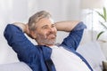 Mature adult man at home close up with hands behind head sitting on couch and thinking dreaming about future plans, gray Royalty Free Stock Photo