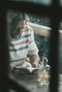 Mature adult man sitting at home in the outdoor terrace reading a book and relaxing enjoying the nature outside in background - Royalty Free Stock Photo