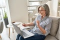 Mature adult old professional woman watching training webinar on laptop at home. Royalty Free Stock Photo