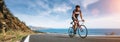 Mature Adult on a racing bike climbing the hill at mediterranean sea landscape coastal road
