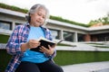 Mature adult student sitting in front off College building and reading school books after attending a university class, Adult Royalty Free Stock Photo