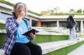 Mature adult student sitting in front off College building and reading school books after attending a university class, Adult Royalty Free Stock Photo