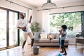 Mature african american dad and his young little son pretending to play the guitar by using a broom in a lounge at home Royalty Free Stock Photo
