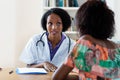 Mature african american female doctor explaining flu and coronavirus symptoms to patient Royalty Free Stock Photo