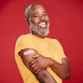 Mature african american man with a beard smiling and looking happy while wearing a bandaid and holding his arm and