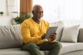 Mature African American Man Using Digital Tablet Sitting At Home Royalty Free Stock Photo