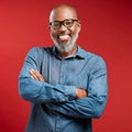 Mature African American man wearing glasses and smiling while posing against a red background. Black male happy with his